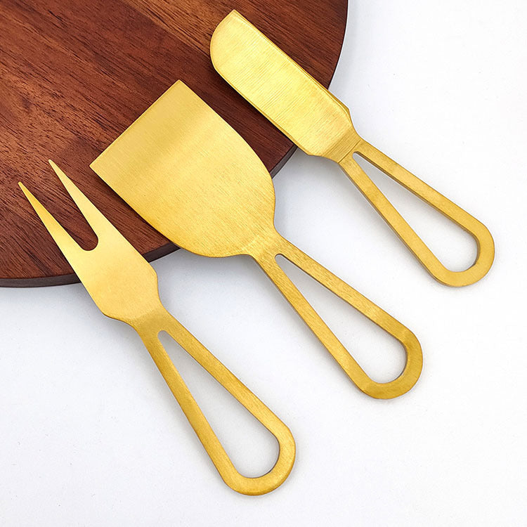 Shopi Vella gold cheese board and knife set with fork, spreader, and slicer on wooden board