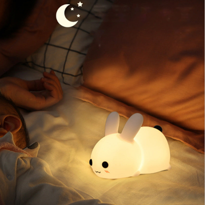 Colorful rabbit silicone night light glowing softly on bed beside sleeping child