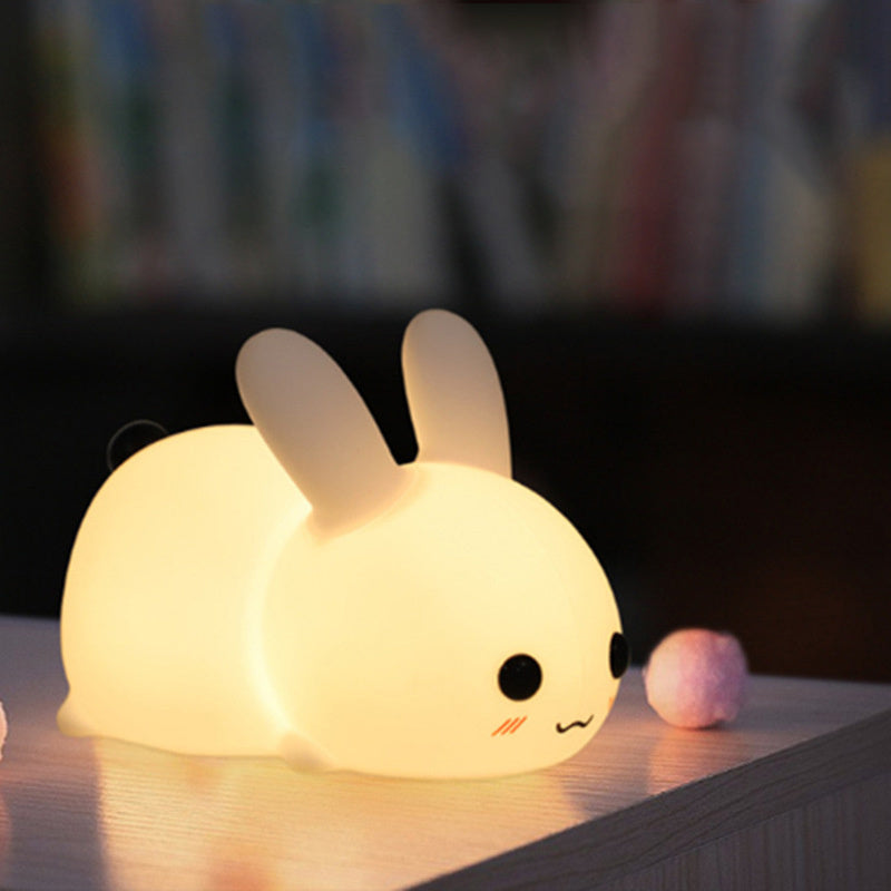 Colorful rabbit silicone night light glowing softly on a wooden surface in a dim room