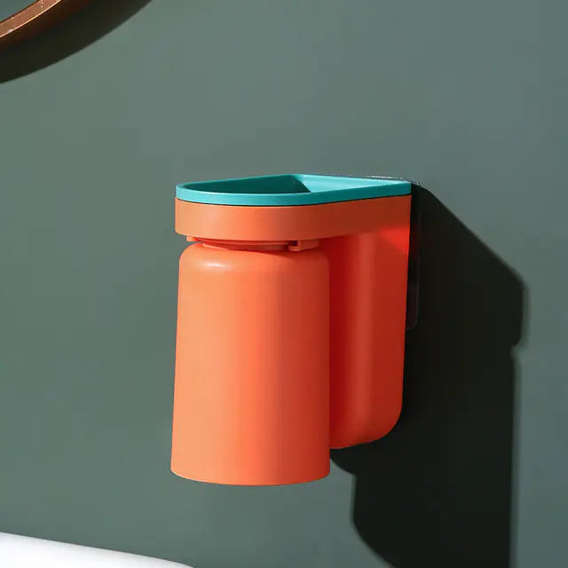 Orange and teal wall-mounted toothbrush holder attached to a dark green bathroom wall