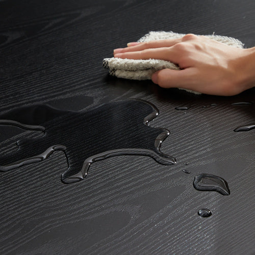 Hand wiping water spill on dark wooden surface of compact dining set for small spaces from Shopi Vella