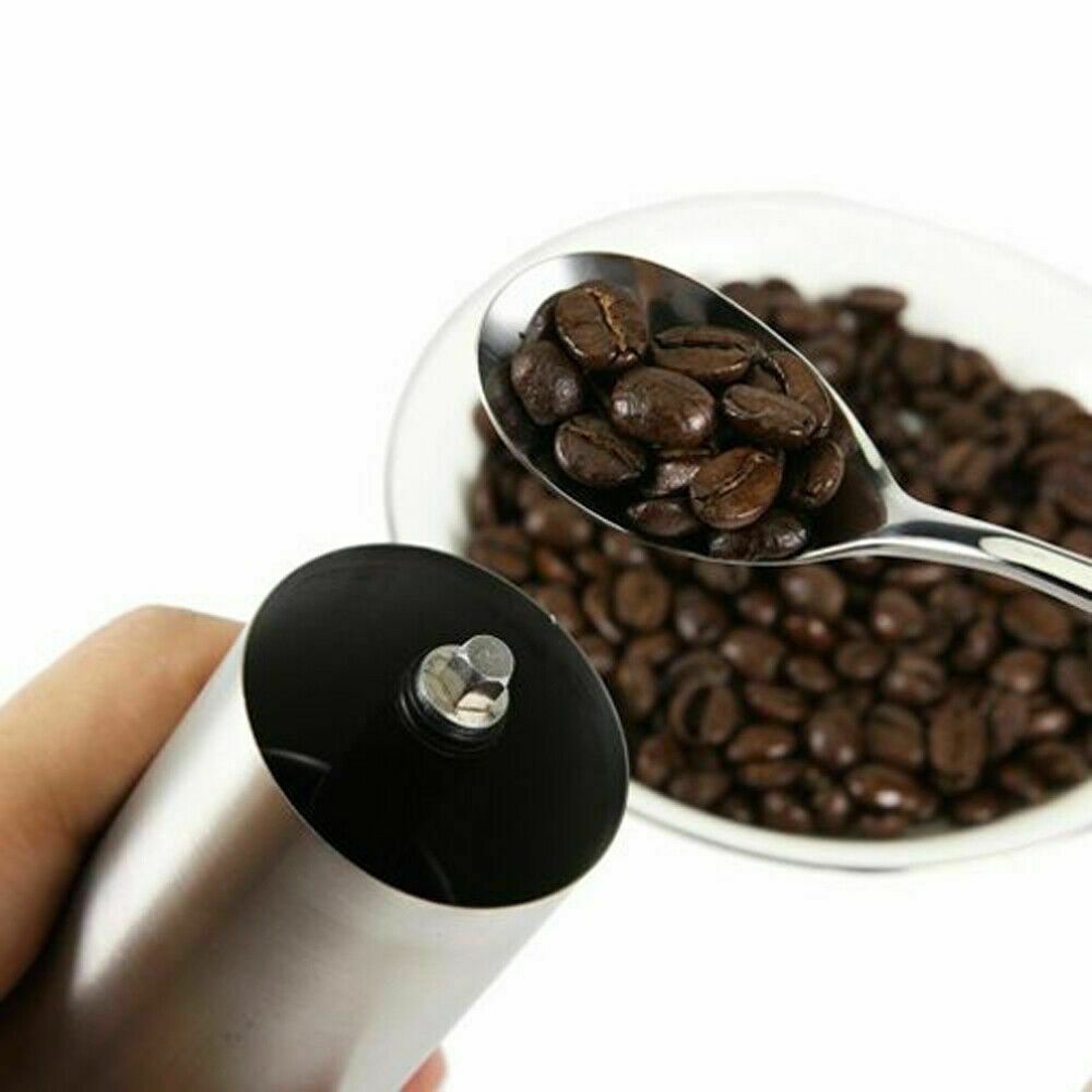 Conical burr coffee bean mill with fresh coffee beans on a spoon and bowl background