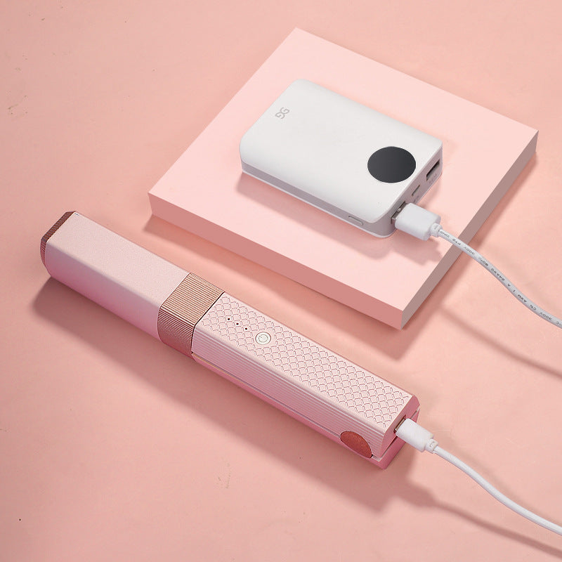 Shopi Vella cordless hair straightener for travel in pink connected to a portable charger on a pink surface