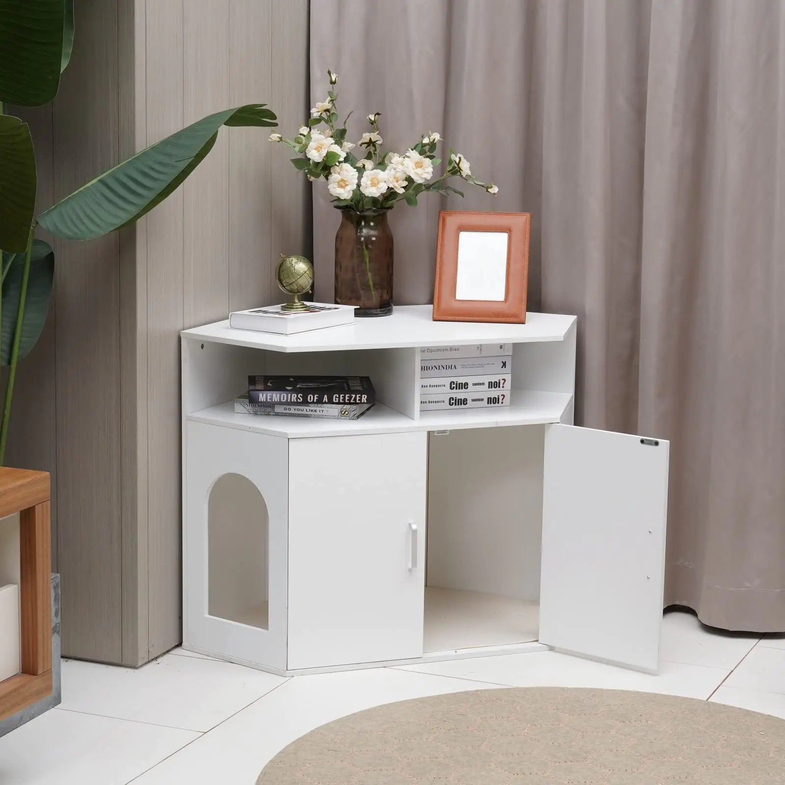 White corner cat litter box furniture with two doors and open shelf decorated with flowers and books