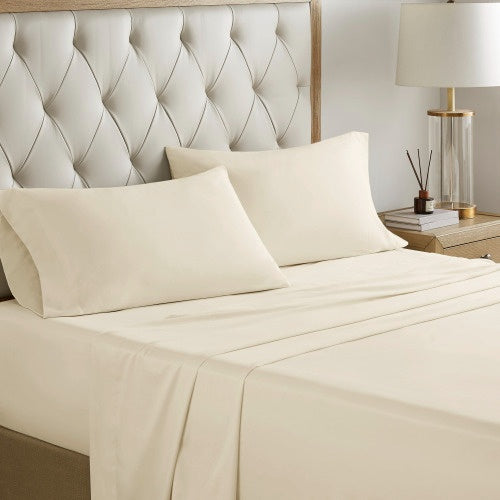 Cream colored cotton bed sheets comforter set on a neatly made bed with tufted headboard