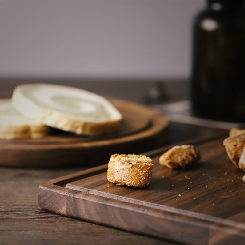 Creative wood cutting board for kitchen by Shopi Vella with bread crumbs and sliced bread on dark wooden surface