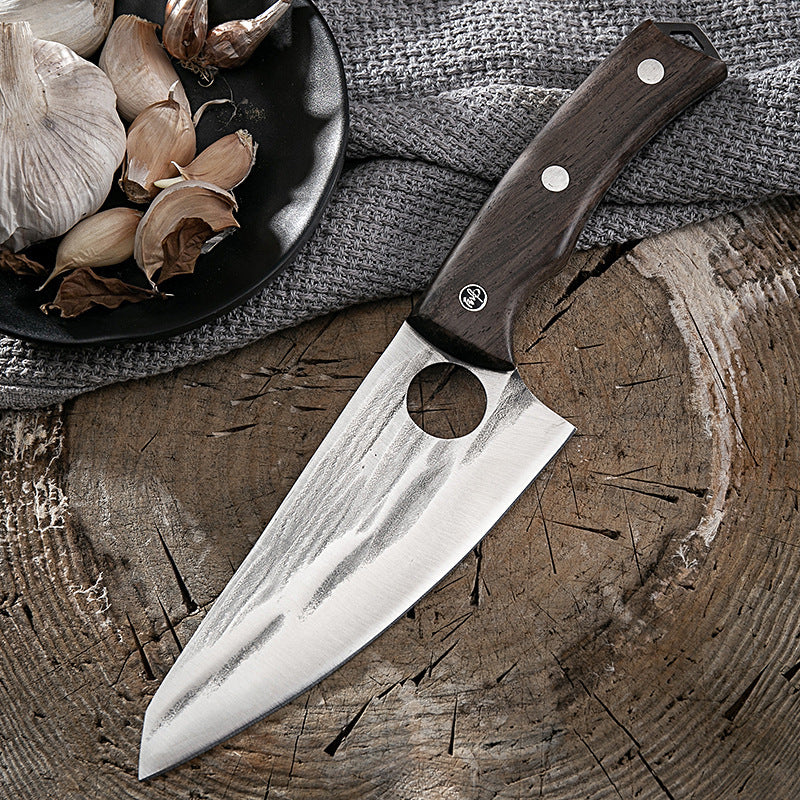 Shopi Vella kitchen deboning knife with wooden handle placed on wooden surface next to garlic cloves