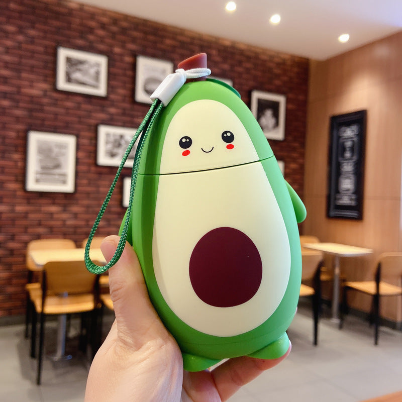 Cute avocado glass container with a smiling face held in hand in a cozy cafe setting