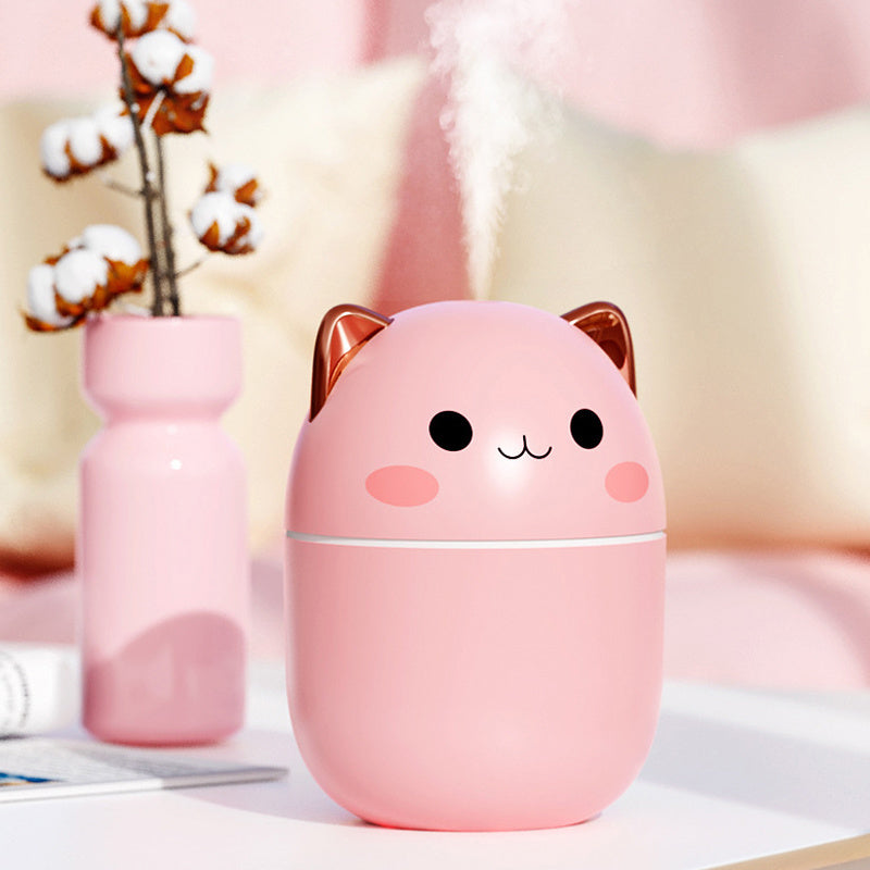 Cute cat air humidifier in pink with adorable face and ears releasing mist on a white table