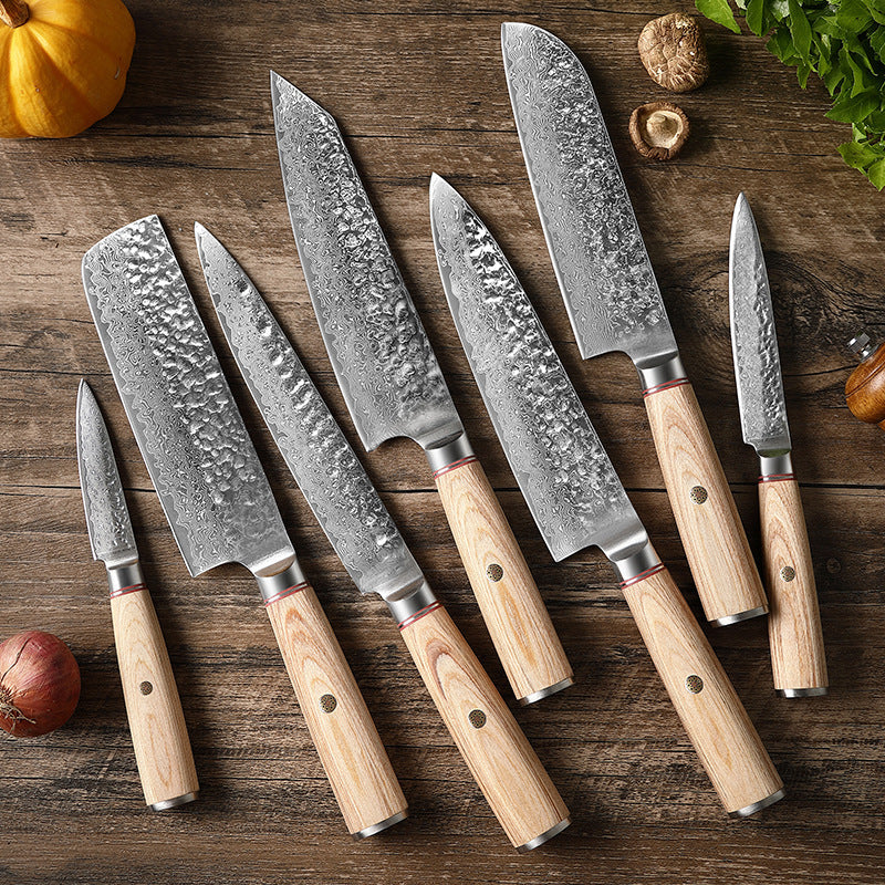 Set of Damascus steel kitchen knives with wooden handles laid out on a wooden surface