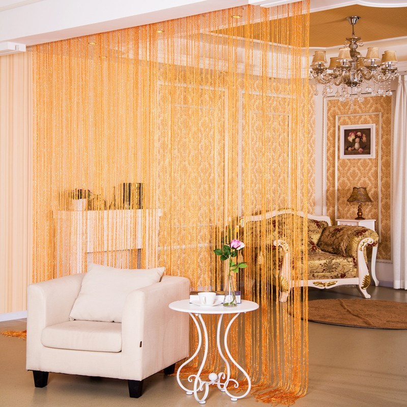Shopi Vella orange decorative thread door curtain hanging in a living room with white armchair and round side table