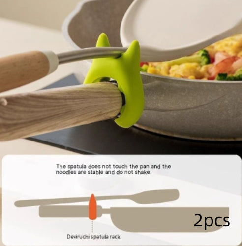 Shopi Vella multifunctional cooking spoon clip in green holding wooden spatula above pan to prevent contact