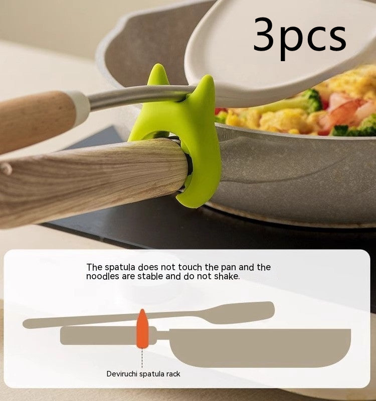 Shopi Vella multifunctional cooking spoon clip in green holds wooden spoon handle above frying pan preventing spatula from touching pan