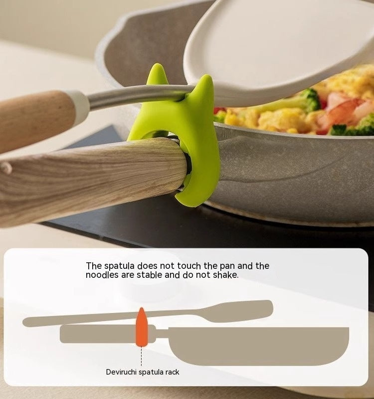 Shopi Vella multifunctional cooking spoon clip in green holding a spatula on a pan handle to keep the spatula off the pan surface