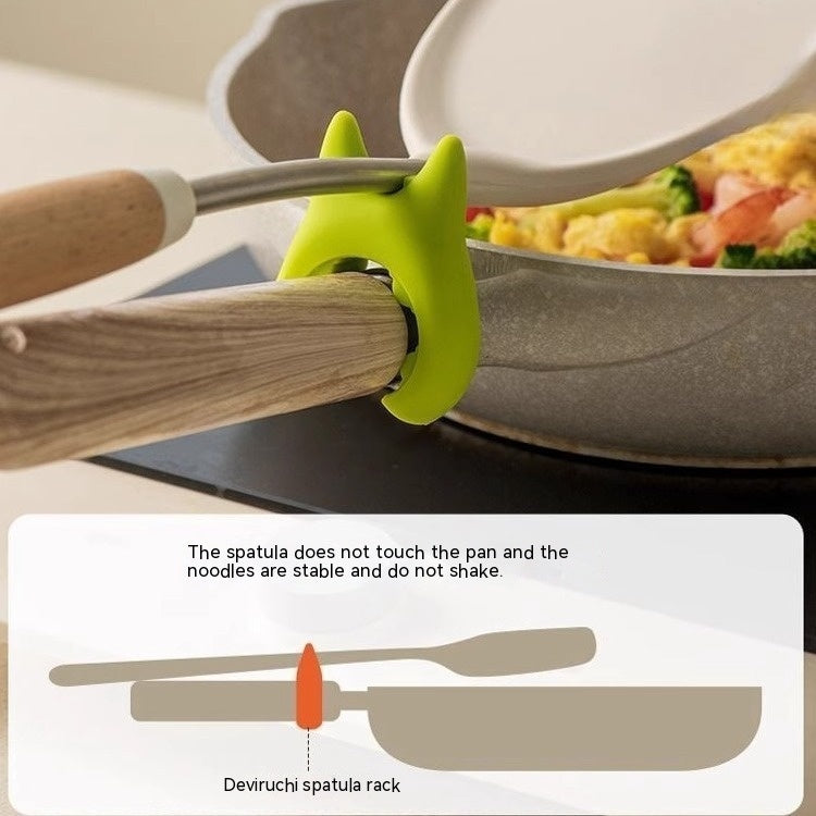 Green multifunctional cooking spoon clip holding a spatula on a pan handle to keep it from touching the pan