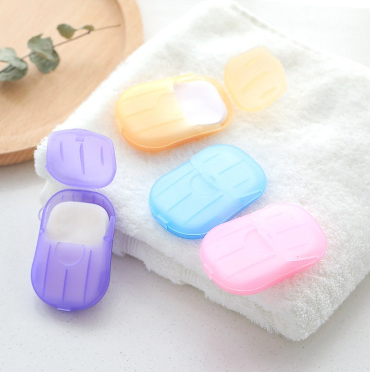 Colorful disposable hand soap paper cases in purple, yellow, blue, and pink on white towel bathroom storage