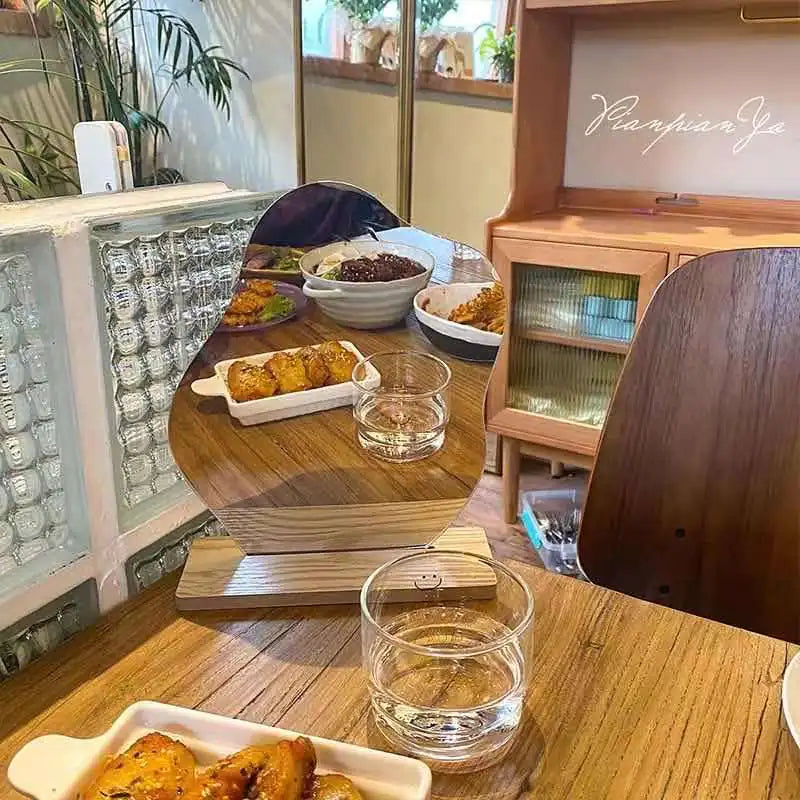 Wooden dorm decor vanity mirror on table reflecting plates of food and glass of water