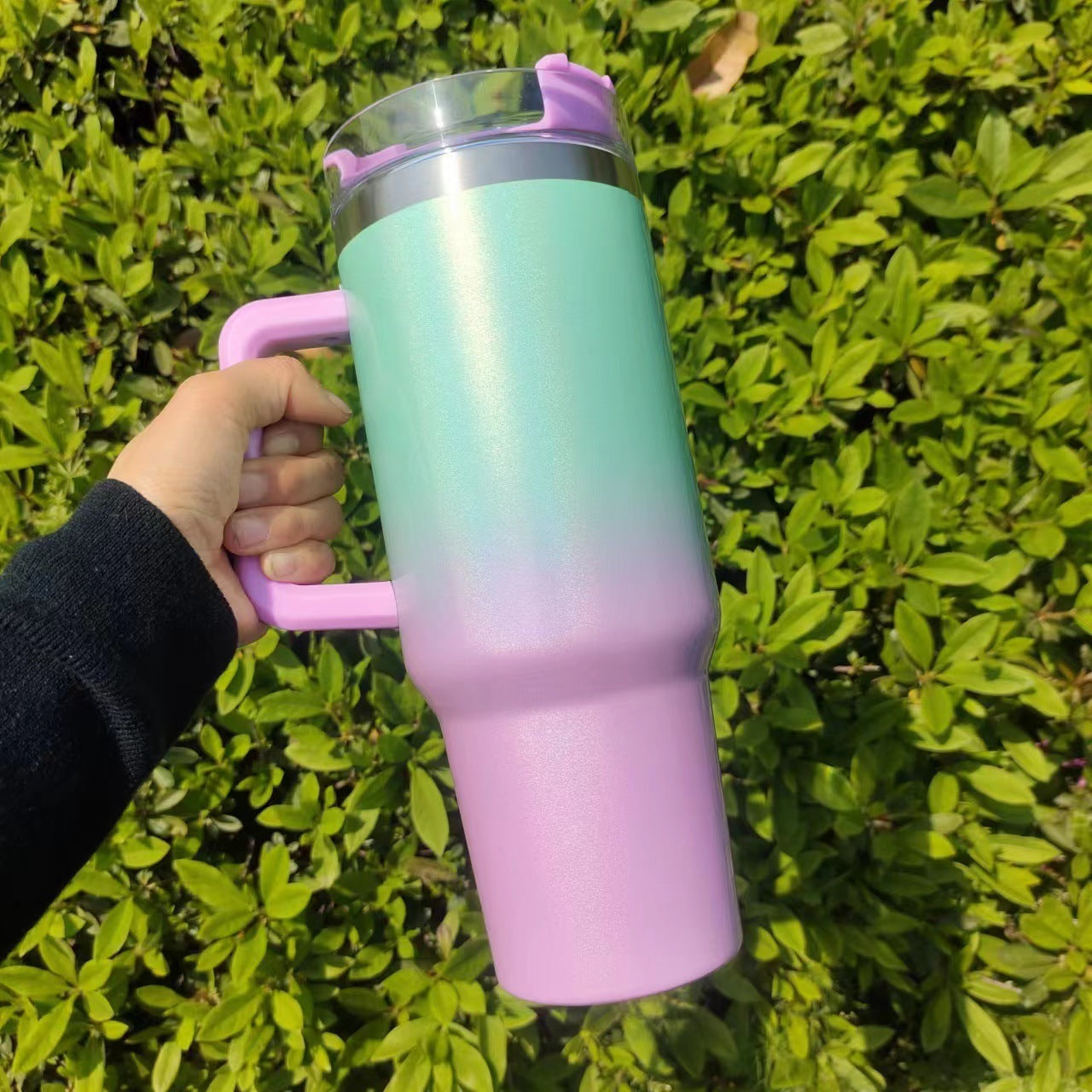 Shopi Vella double-layer stainless steel cup in gradient green and pink with handle held outdoors