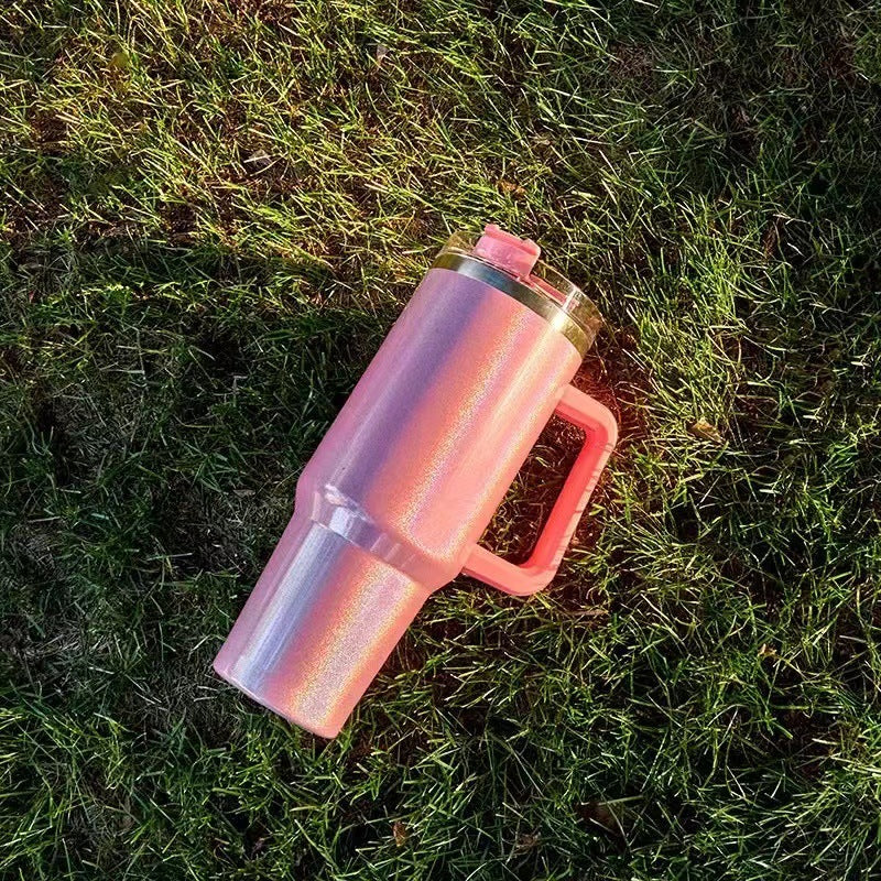Shopi Vella double-layer stainless steel cup in pink with handle and clear lid on grass