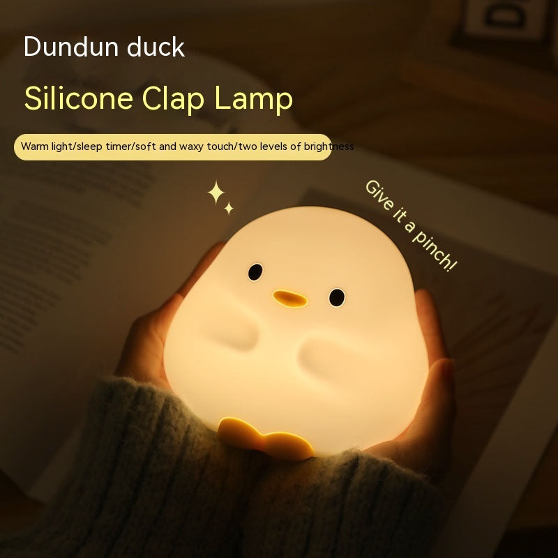 Cartoon LED sleeping light shaped like a cute silicone duck held in hands with warm glowing light