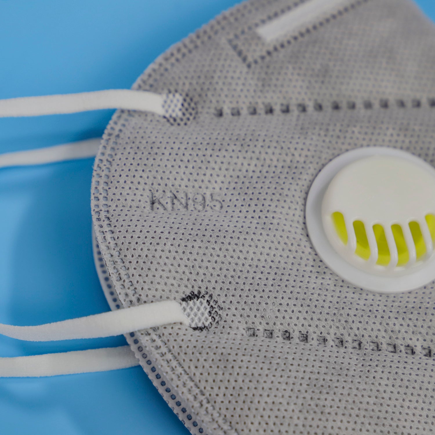 Close-up of a gray dustproof industrial protective mask with white valve and elastic straps