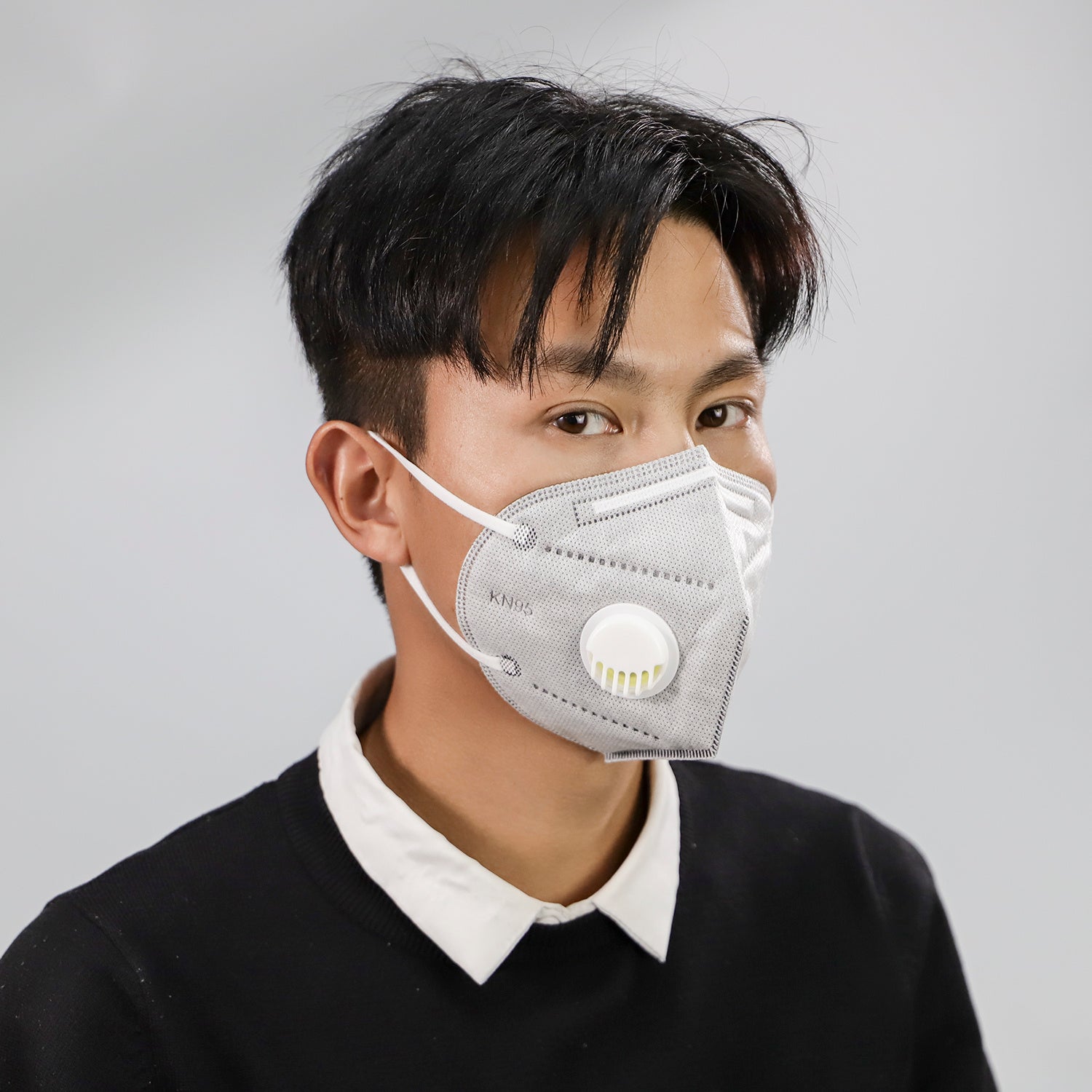 Young man wearing dustproof industrial protective mask with valve in gray color