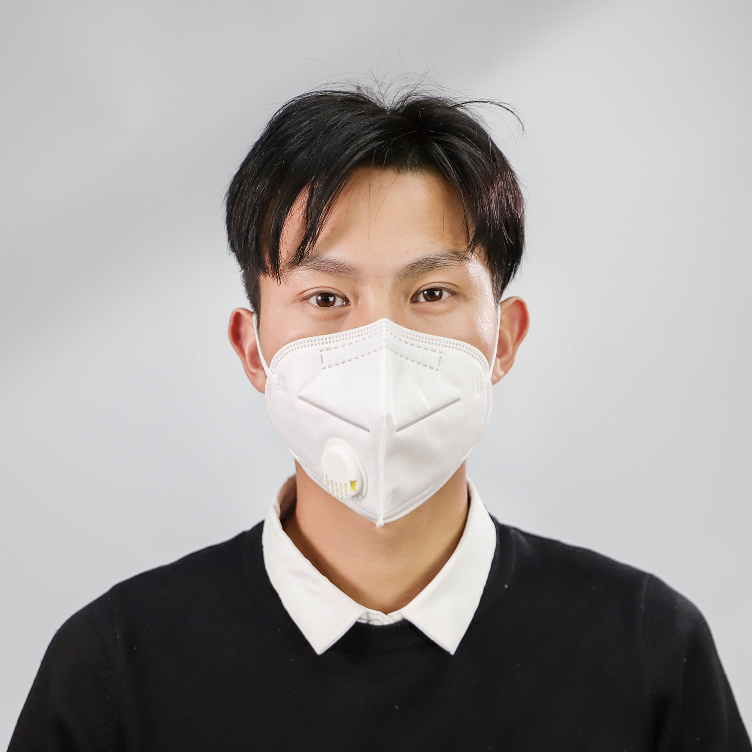 Person wearing a white dustproof industrial protective mask with valve for safe breathing