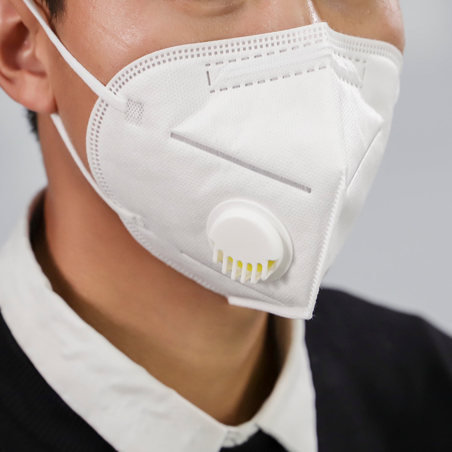 Close-up of person wearing a white dustproof industrial protective mask with an air valve