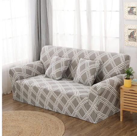 Gray elastic sofa cover with white geometric pattern on a two-seater sofa with matching pillows in bright living room