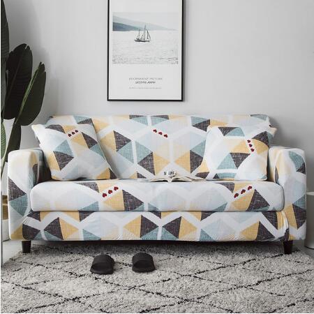 Colorful geometric elastic sofa cover on two-seater couch with matching pillows in living room