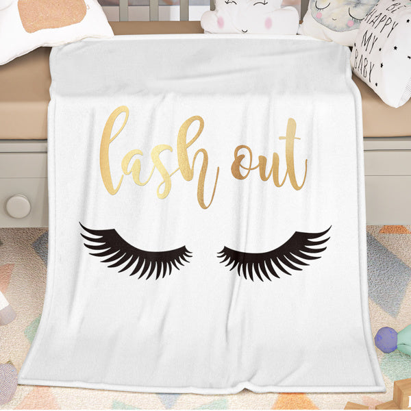 Shopi Vella eyelash print throw blanket with gold lash out text and black eyelash design on white background