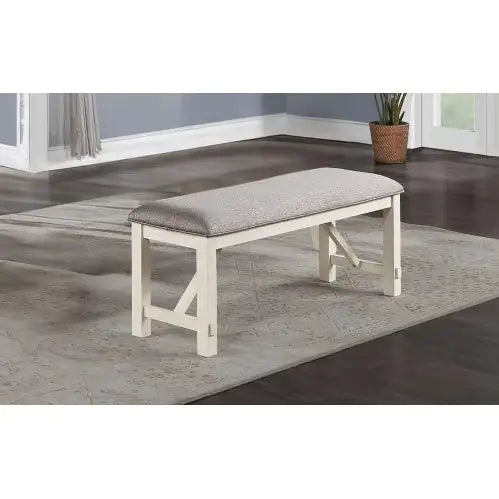 Fabric cushioned dining seating bench with white wooden legs placed on a gray rug in a modern dining room
