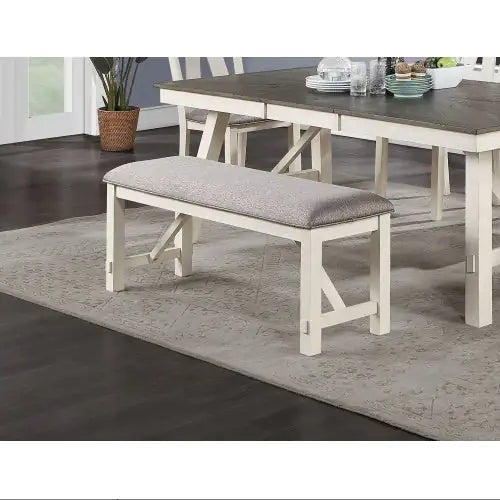Fabric cushioned dining seating bench with white wooden legs and gray padded cushion near rustic dining table