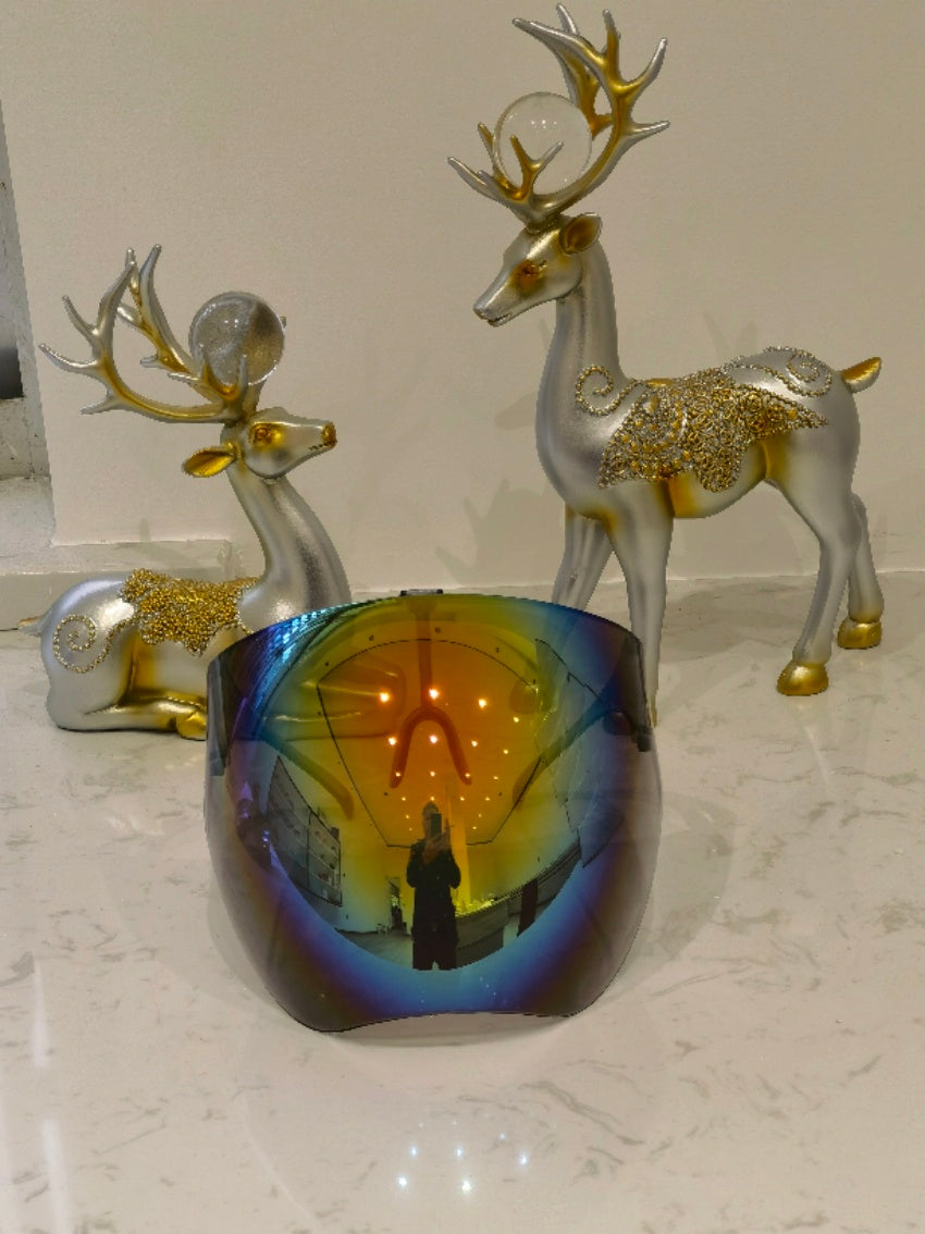 Shopi Vella faceshield protective glasses with reflective blue tint displayed on marble surface with decorative gold and silver reindeer