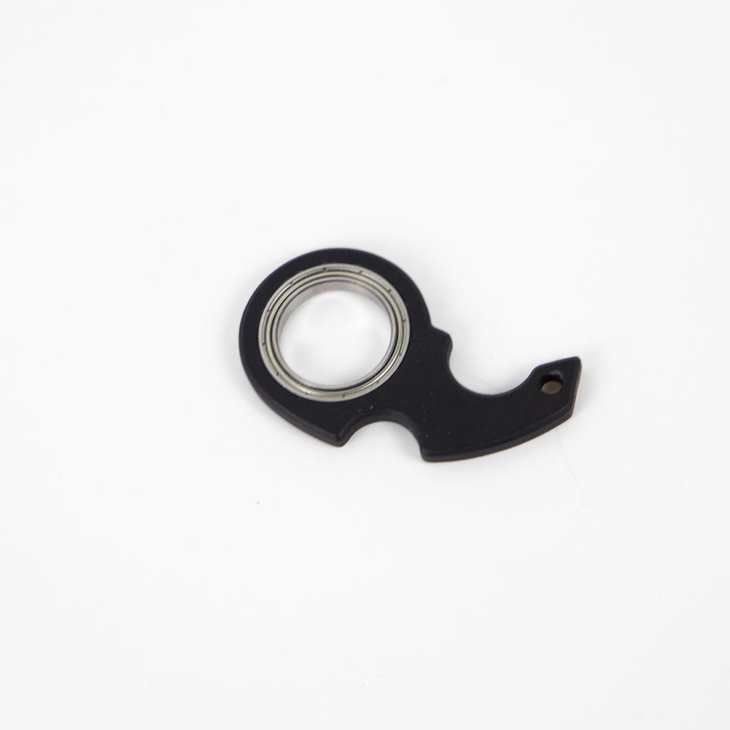 Black finger spinner bottle opener with metal bearing and compact design by Shopi Vella