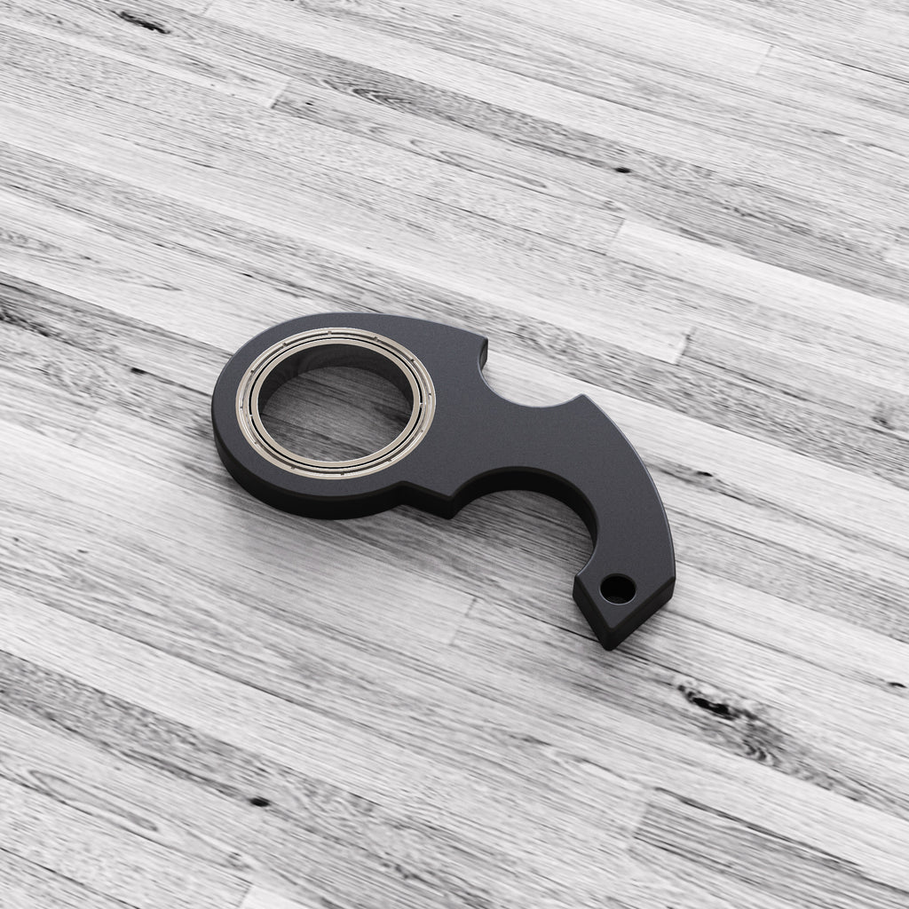 Shopi Vella black finger spinner bottle opener with metal bearings on wooden surface