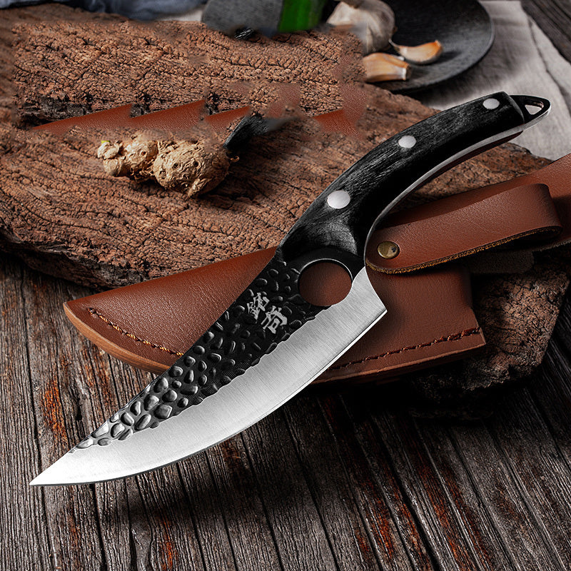 Shopi Vella forged boning knife with hammered blade and black handle resting on leather sheath