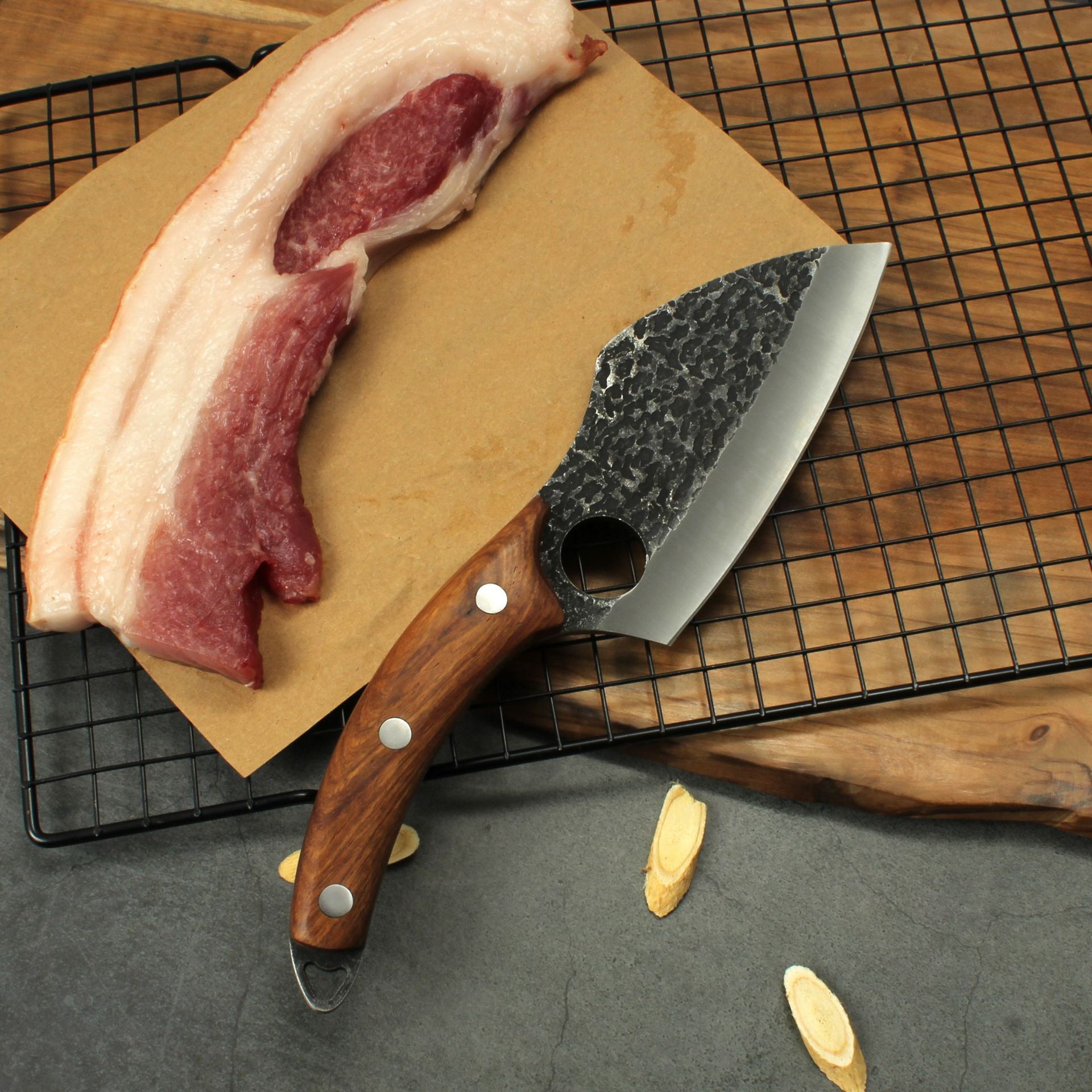 Shopi Vella forged boning knife with wooden handle beside raw meat on cooling rack