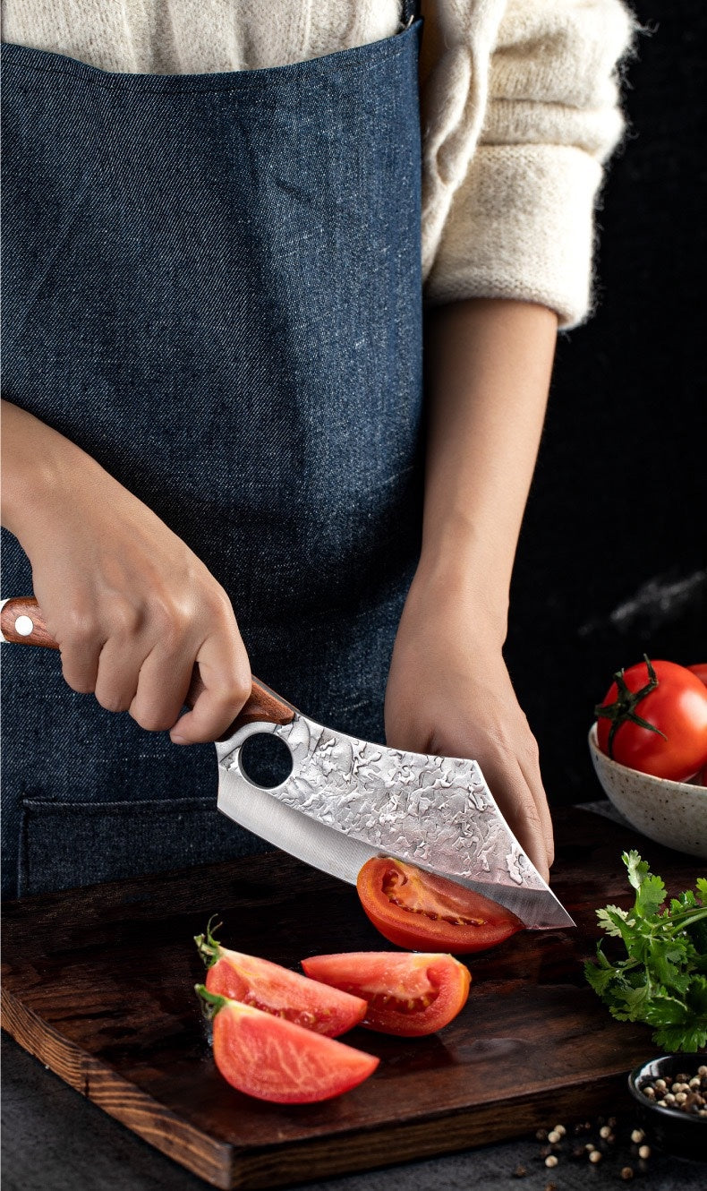Shopi Vella forged small kitchen knife cutting fresh tomato on wooden board with herbs nearby