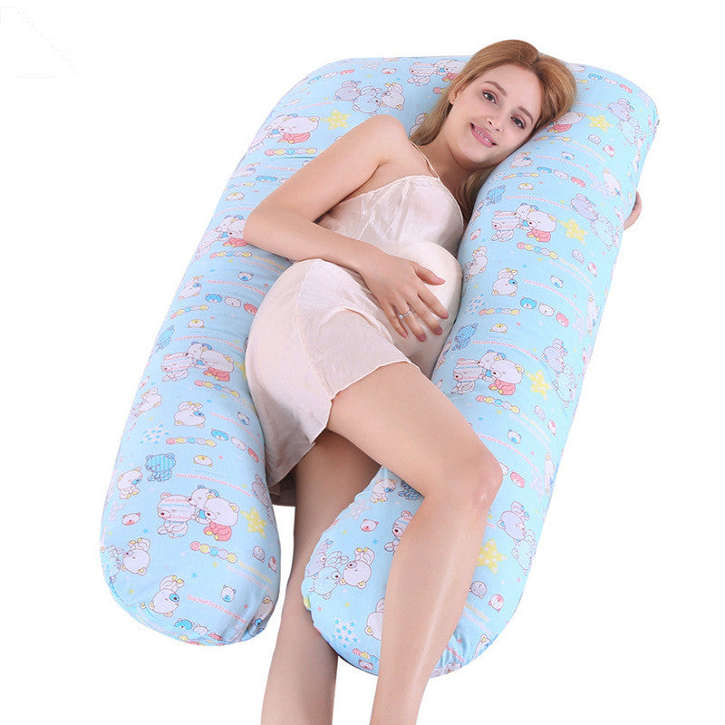Pregnant woman resting on a blue full body maternity pillow with cute animal prints