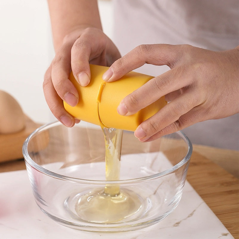 Shopi Vella yellow egg shell opener tool cracking egg into clear glass bowl on kitchen counter