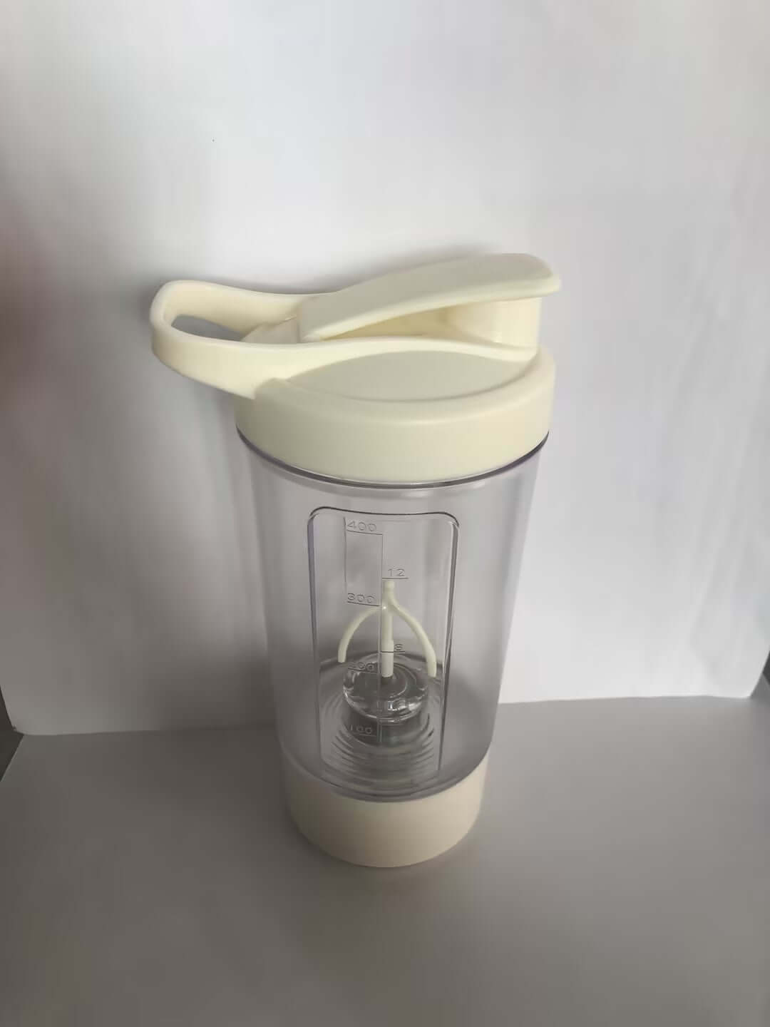 Shopi Vella electric protein shaker bottle in white with clear container and mixing blades for kitchen storage