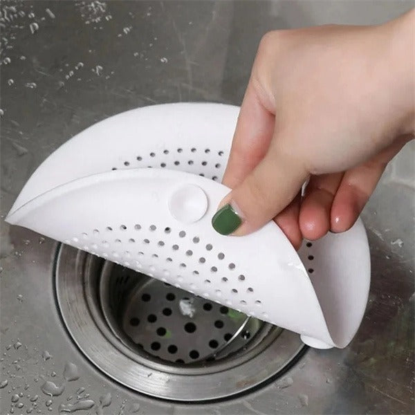 Shopi Vella white kitchen sink hair filter being held over a stainless steel sink drain