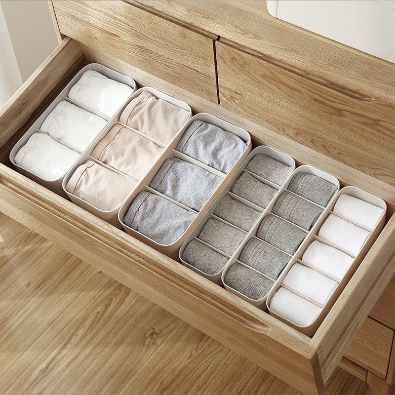 Underwear drawer organizer by Shopi Vella with multiple white compartments neatly storing folded underwear in a wooden drawer