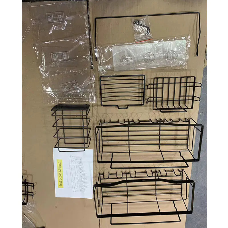 Black metal wall-mounted shower storage rack components laid out with assembly instructions on a cardboard surface