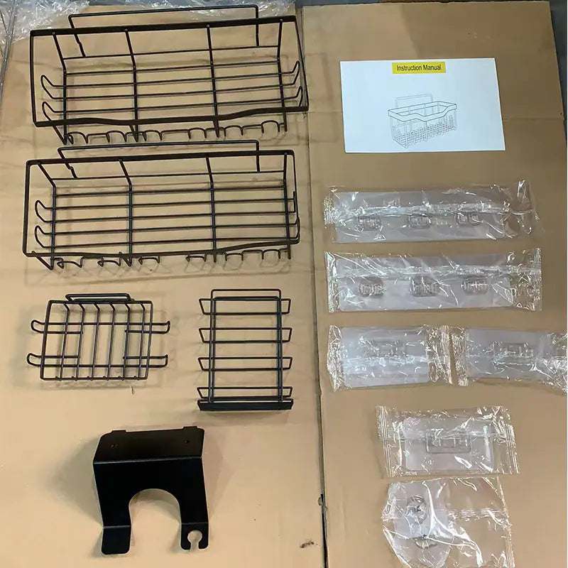 Unassembled black metal wall-mounted shower storage rack with multiple baskets and hooks laid out with installation hardware