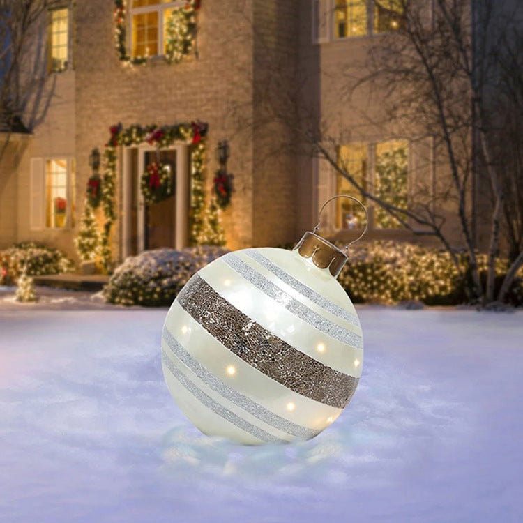 Shopi Vella giant outdoor Christmas ornament ball with silver glitter stripes on snow in front of a decorated house