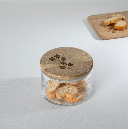 Shopi Vella glass jar with wooden lid featuring a leaf design, storing small bread slices