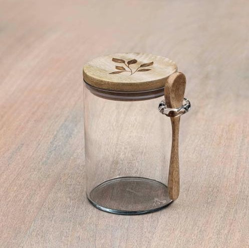 Shopi Vella glass kitchen storage jar with wooden lid and attached wooden spoon on a light wood surface