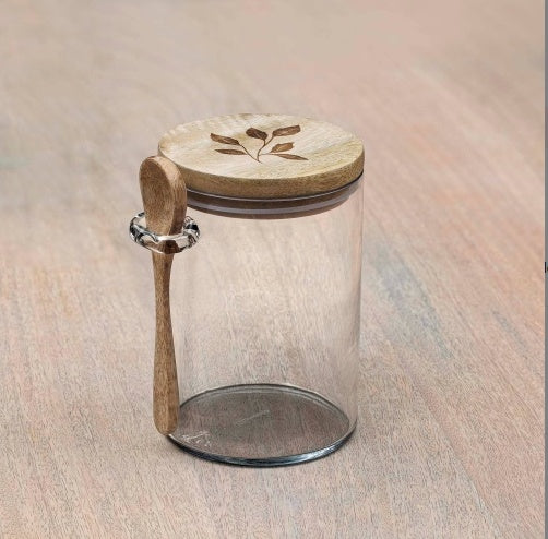 Shopi Vella glass kitchen storage jar with wooden lid and attached wooden spoon on wood surface